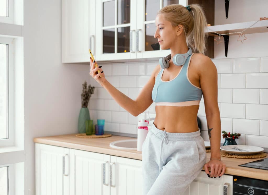 Fit nő a konyhában telefonozik – Adipex hatóanyaga a napi motivációhoz